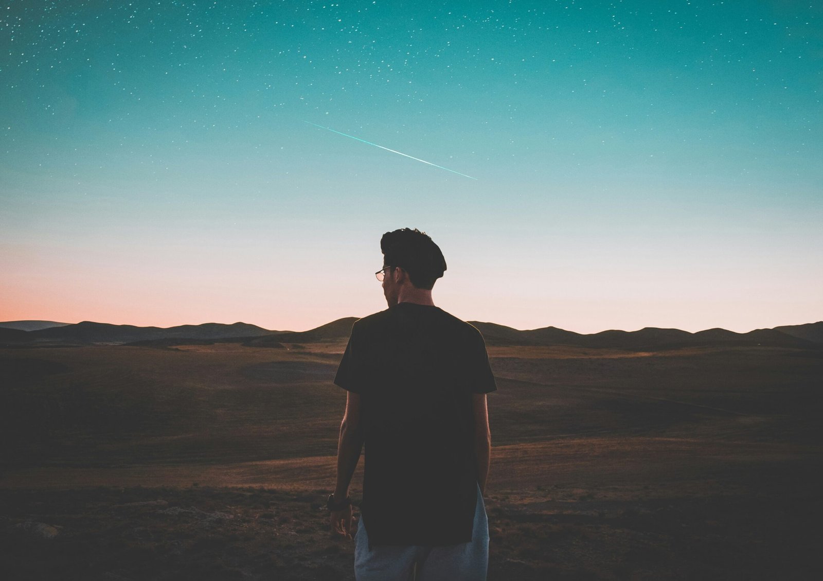 man wearing black top standing in front of mountain