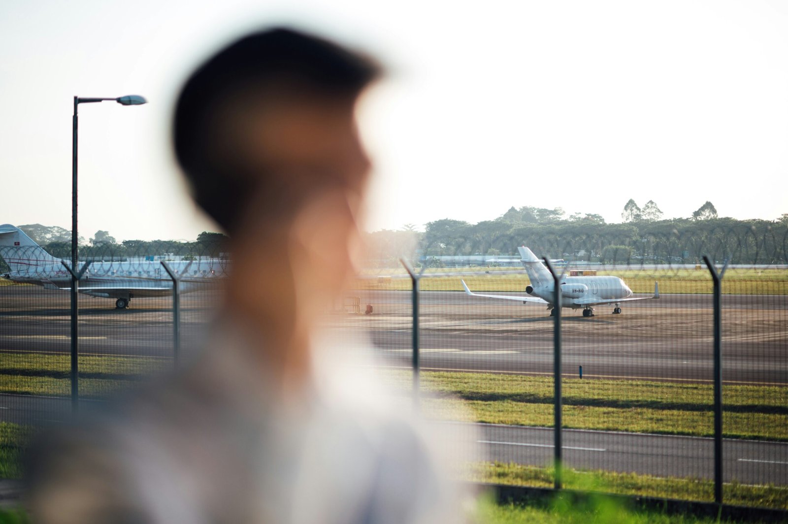 man in white shirt standing near fence during daytime