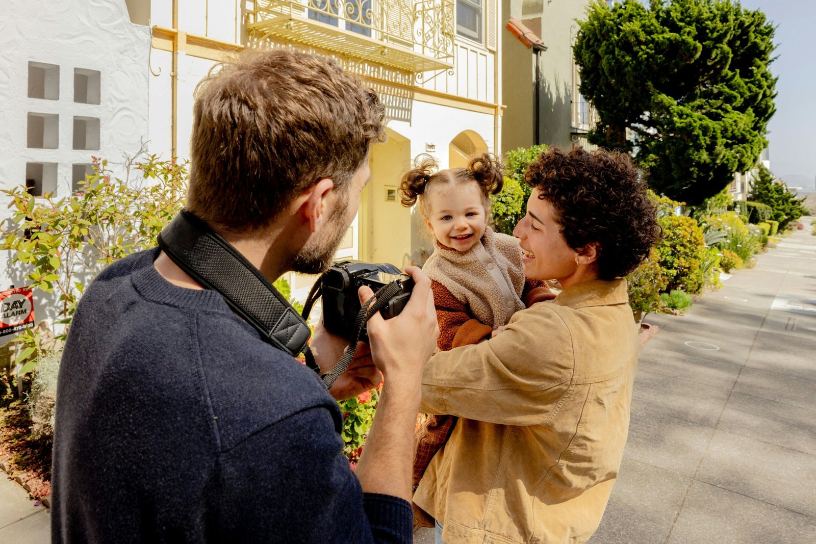 A man taking a picture of a woman holding a baby